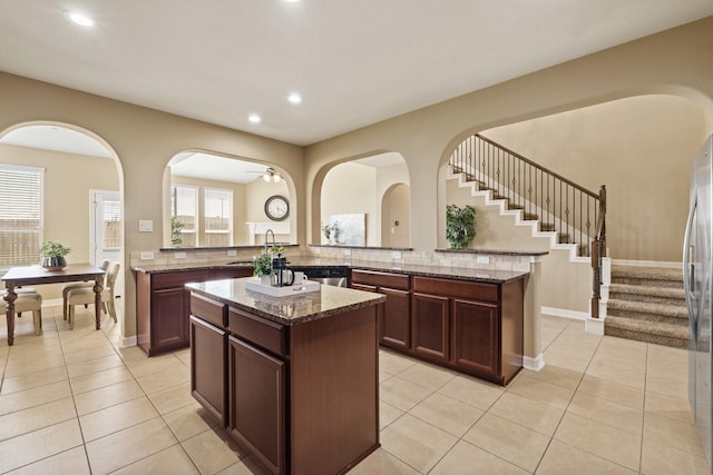 kitchen with stone countertops, a sink, a kitchen island, recessed lighting, and light tile patterned floors