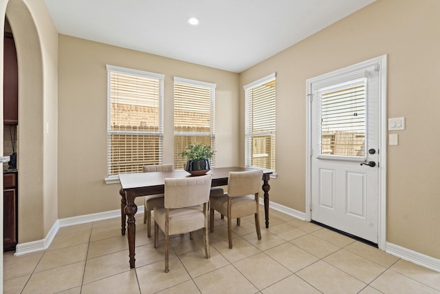 dining area with light tile patterned floors, baseboards, arched walkways, and recessed lighting