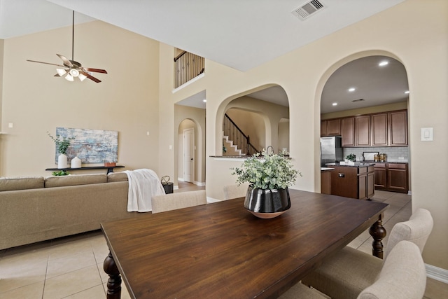 dining space with ceiling fan, visible vents, arched walkways, and light tile patterned flooring