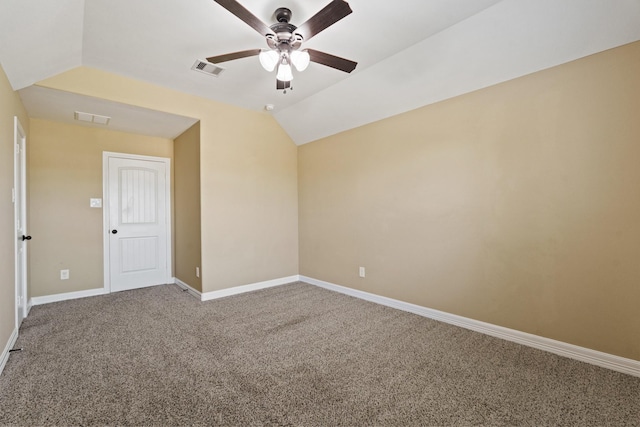 carpeted spare room with lofted ceiling, baseboards, visible vents, and ceiling fan