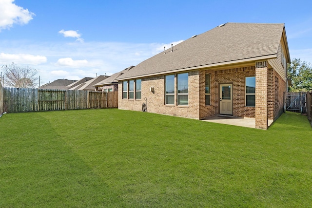 back of property featuring a patio, roof with shingles, a fenced backyard, a lawn, and brick siding