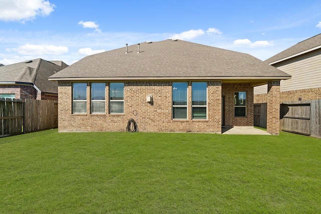 back of house with a yard, brick siding, and a fenced backyard