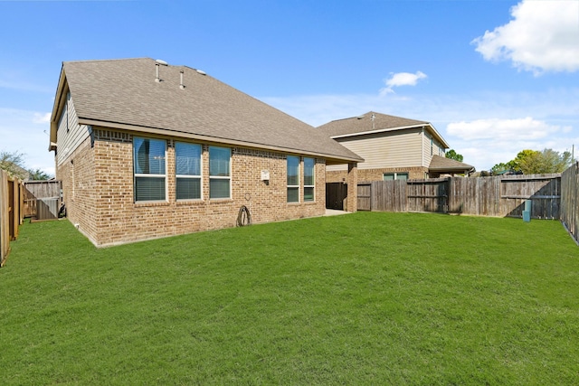 rear view of property with brick siding, a fenced backyard, and a yard