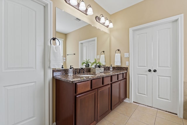 full bathroom with a sink, visible vents, double vanity, and tile patterned flooring