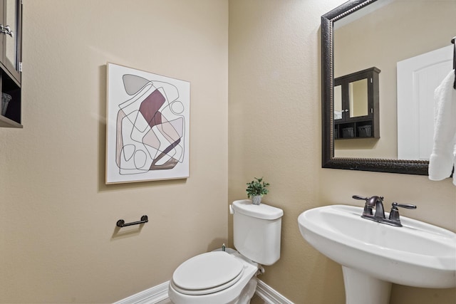 bathroom with a sink, baseboards, and toilet