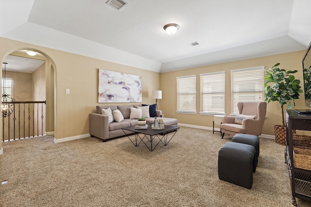 carpeted living room with a raised ceiling, baseboards, visible vents, and arched walkways