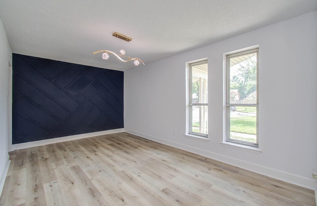 empty room with baseboards, a textured ceiling, and light wood-style flooring