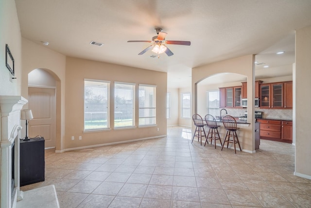 interior space featuring stainless steel microwave, a kitchen breakfast bar, arched walkways, and brown cabinets