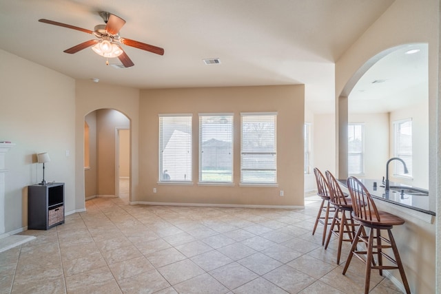 interior space with light tile patterned floors, arched walkways, visible vents, and ceiling fan