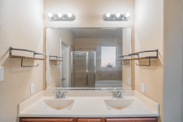 full bathroom with a shower stall, double vanity, and a sink