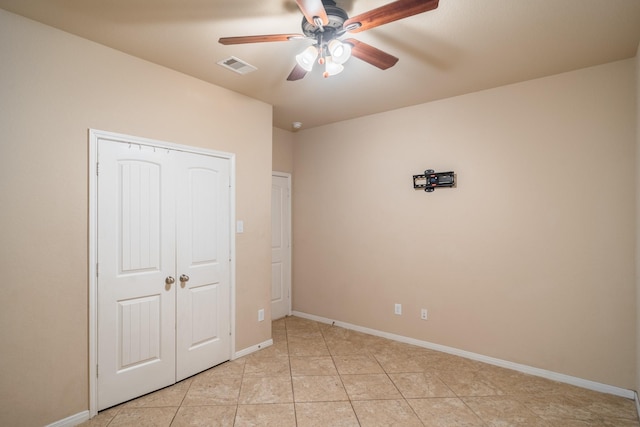 unfurnished bedroom featuring visible vents, a ceiling fan, a closet, light tile patterned floors, and baseboards