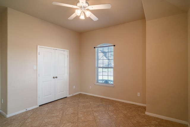 unfurnished bedroom with ceiling fan, a closet, baseboards, and light tile patterned flooring