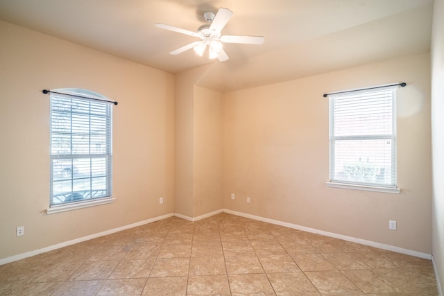 spare room featuring light tile patterned floors, a ceiling fan, and baseboards