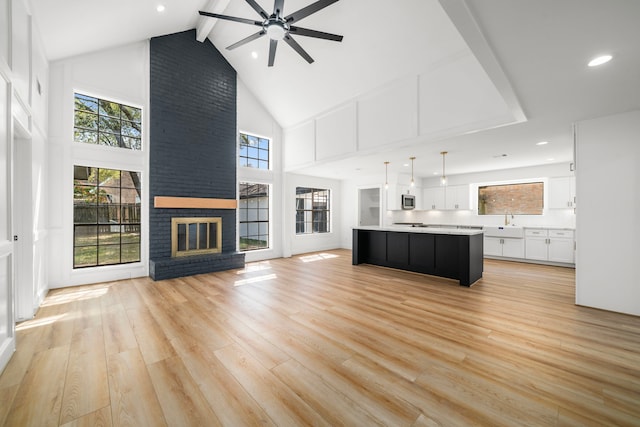 unfurnished living room featuring a ceiling fan, light wood-style flooring, and a healthy amount of sunlight