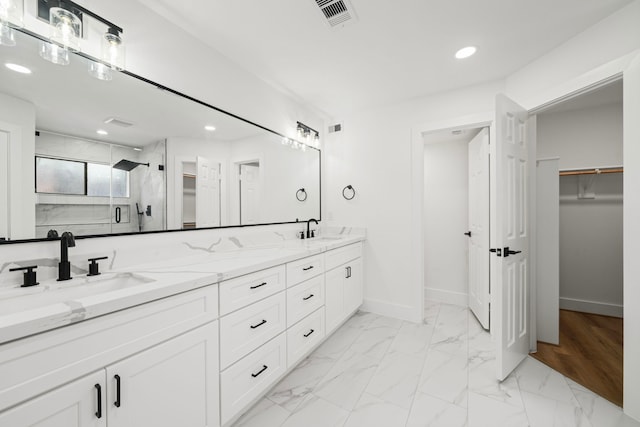 bathroom with a shower stall, a walk in closet, baseboards, marble finish floor, and a sink