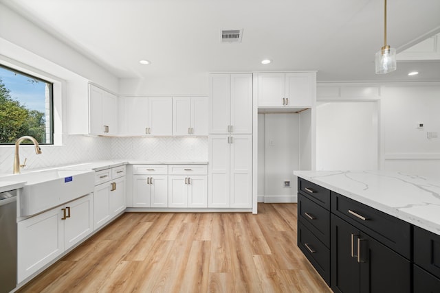 kitchen with dark cabinetry, visible vents, a sink, light wood-style floors, and white cabinetry