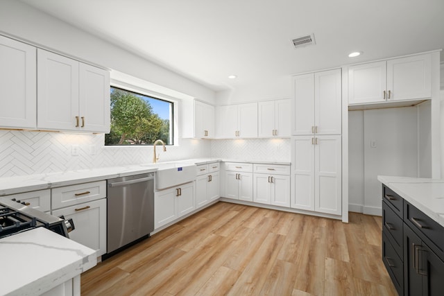 kitchen with light stone counters, a sink, white cabinets, dishwasher, and light wood-type flooring