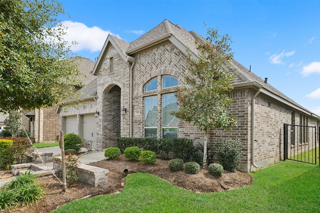 french country home featuring a front yard, brick siding, and an attached garage