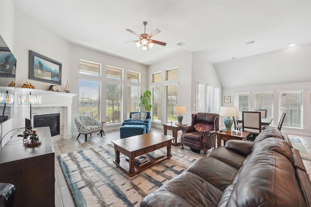 living area featuring a high end fireplace, visible vents, and a ceiling fan