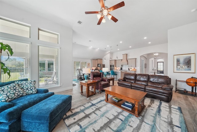 living area with a ceiling fan, light wood-style floors, arched walkways, and visible vents