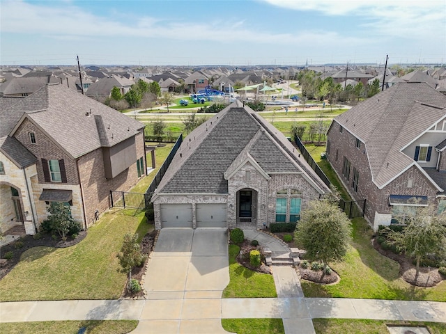 view of front facade featuring brick siding, a residential view, driveway, and an attached garage