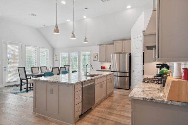 kitchen featuring visible vents, an island with sink, lofted ceiling, appliances with stainless steel finishes, and a sink