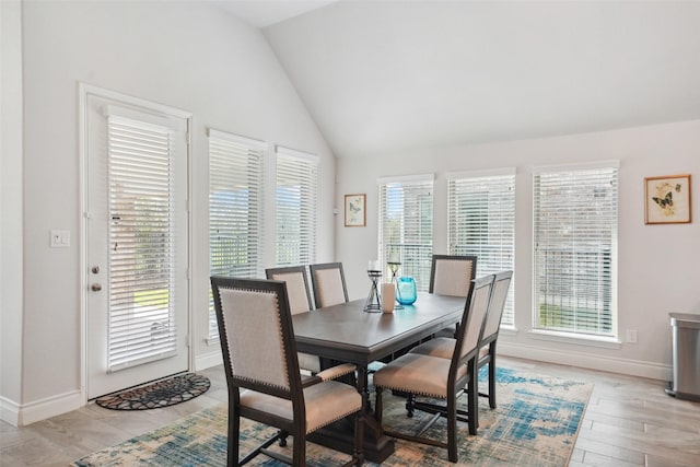 dining area with light wood-style floors, baseboards, and vaulted ceiling