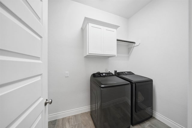 laundry area with wood finished floors, baseboards, cabinet space, and washing machine and dryer