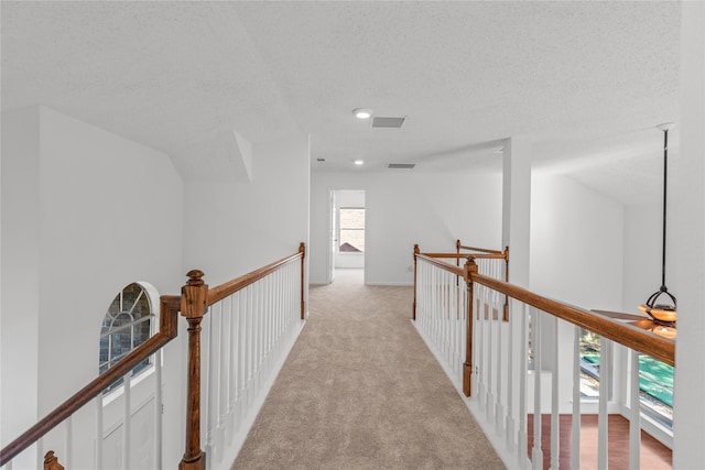 corridor with recessed lighting, an upstairs landing, visible vents, a textured ceiling, and light colored carpet