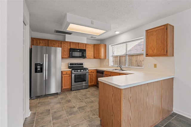 kitchen featuring a sink, visible vents, stainless steel appliances, light countertops, and a peninsula