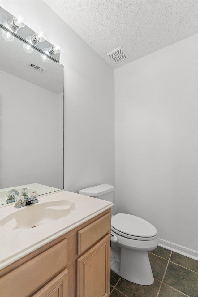 half bath with a textured ceiling, visible vents, toilet, and tile patterned flooring
