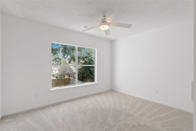 carpeted empty room with a textured ceiling, ceiling fan, visible vents, and baseboards