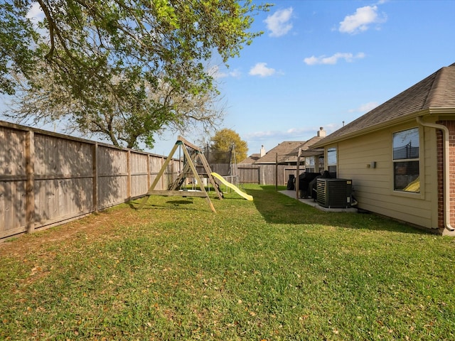 view of yard featuring central AC, a fenced backyard, and a playground