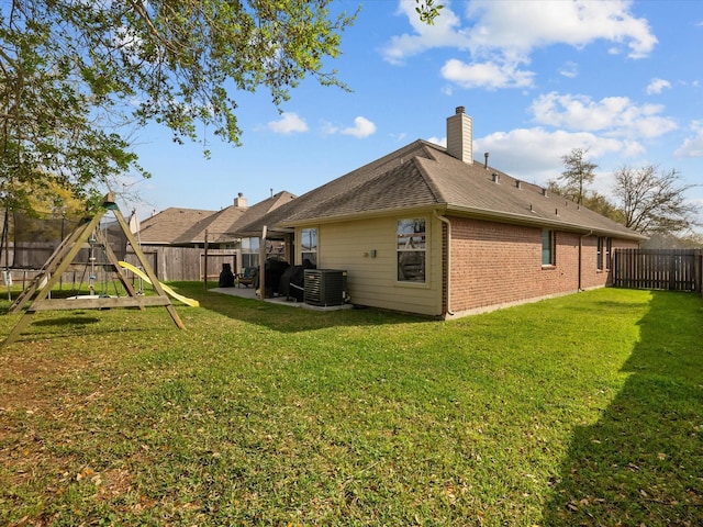 back of house featuring central air condition unit, a fenced backyard, a playground, a yard, and a patio area