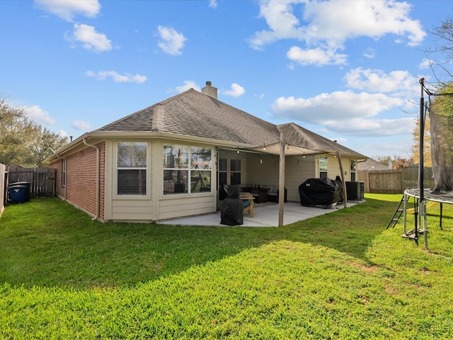 back of property featuring a trampoline, central air condition unit, roof with shingles, a fenced backyard, and a patio area