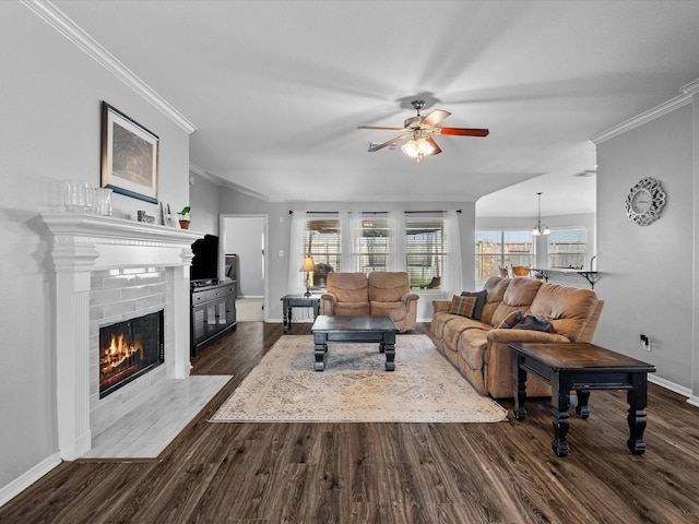 living area featuring crown molding, baseboards, a fireplace, a ceiling fan, and dark wood-style flooring