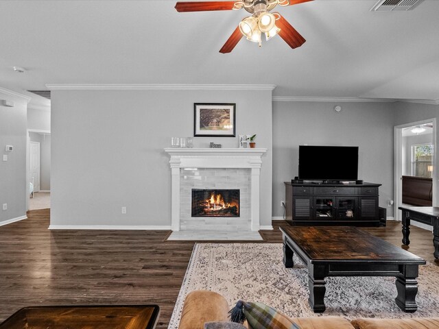 living area with wood finished floors, a ceiling fan, baseboards, and ornamental molding