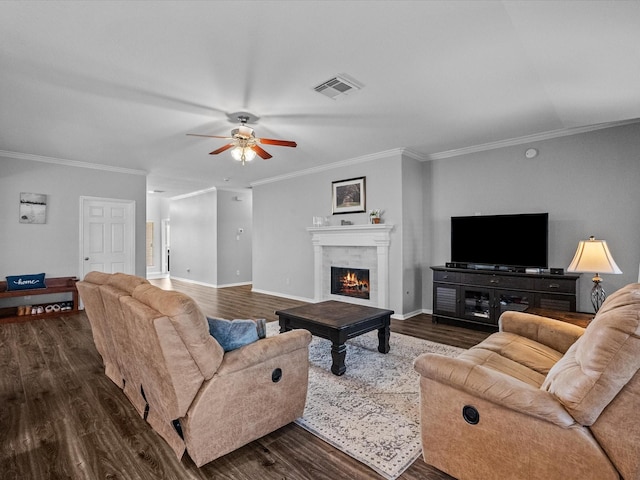 living room featuring visible vents, a ceiling fan, a lit fireplace, baseboards, and dark wood-style flooring