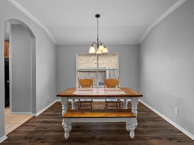 dining space with baseboards, arched walkways, an inviting chandelier, and crown molding