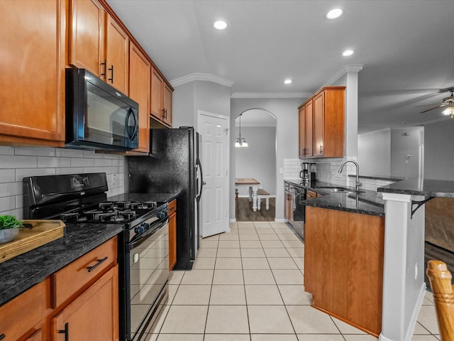 kitchen with light tile patterned floors, brown cabinetry, a peninsula, a sink, and black appliances