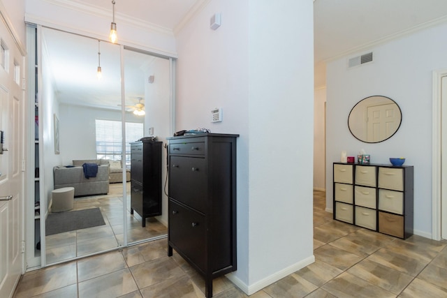 corridor featuring tile patterned flooring, visible vents, baseboards, and ornamental molding