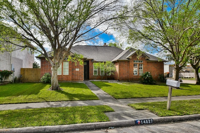 single story home featuring a front yard, fence, brick siding, and roof with shingles