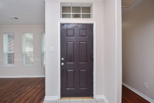 entrance foyer with visible vents, baseboards, wood finished floors, and crown molding