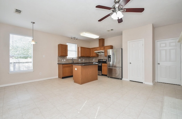 kitchen featuring visible vents, stainless steel appliances, under cabinet range hood, dark countertops, and backsplash