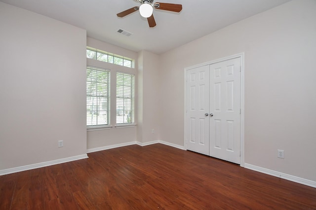 unfurnished bedroom featuring multiple windows, dark wood-style floors, and baseboards