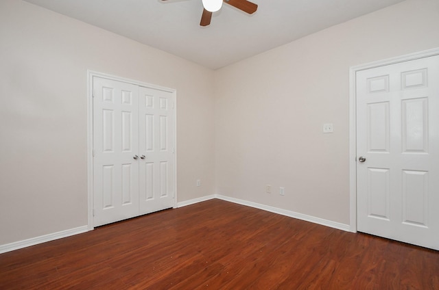 unfurnished bedroom with dark wood-type flooring, a ceiling fan, and baseboards