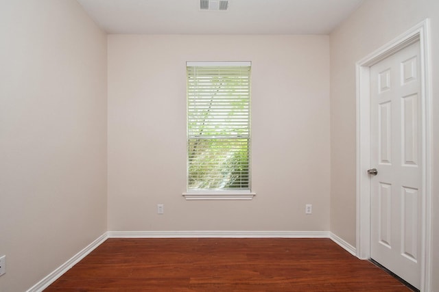 unfurnished room with visible vents, baseboards, and dark wood-style flooring