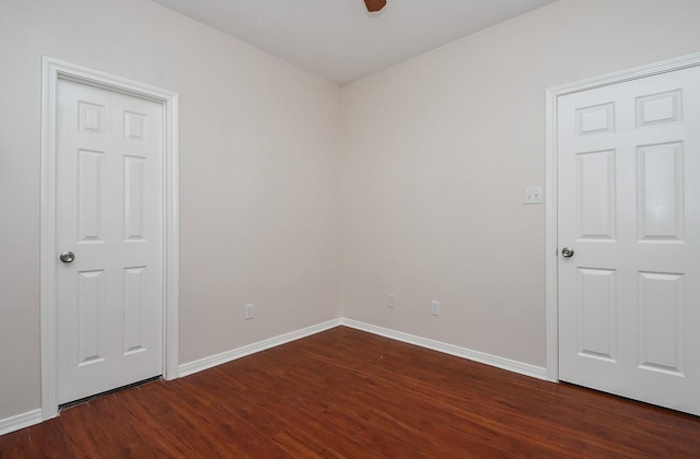 empty room featuring baseboards, dark wood finished floors, and a ceiling fan