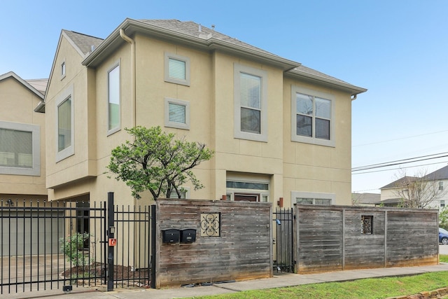 exterior space with a fenced front yard, stucco siding, and a gate