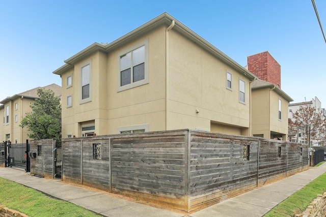 view of home's exterior with a fenced front yard, stucco siding, and a gate